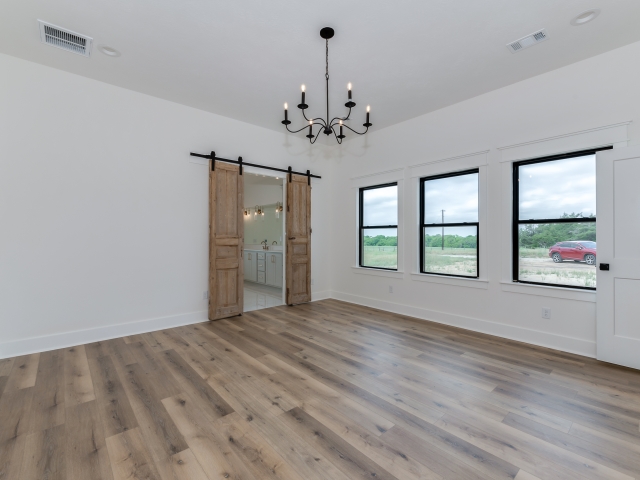 Bedroom with sliding wood barn doors and large windows with black trim.