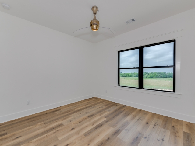 Bedroom with black-trimmed windows and wood flooring.