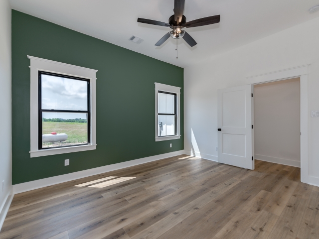 Bedroom with green accent wall and large windows.