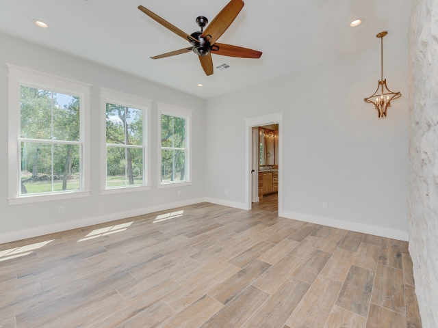 Bedroom with stone wall and large windows.