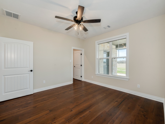 Bedroom with deep wood flooring and white doors.