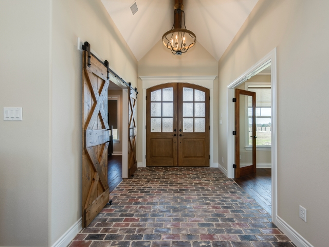 Foyer of the Taylor Project by LaFollette Custom Homes featuring brick flooring and sliding barn doors.