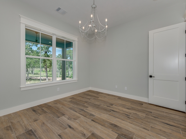 LaFollette Custom Homes bedroom with wood flooring and chandelier.