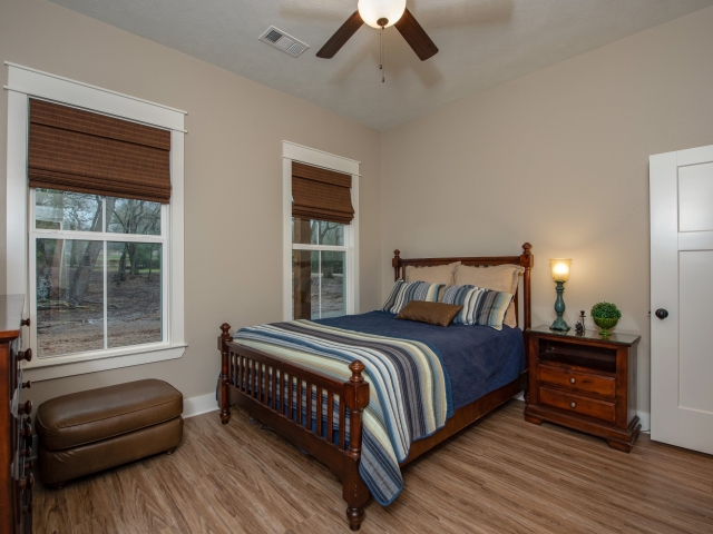 Bedroom with wood furniture and large windows.