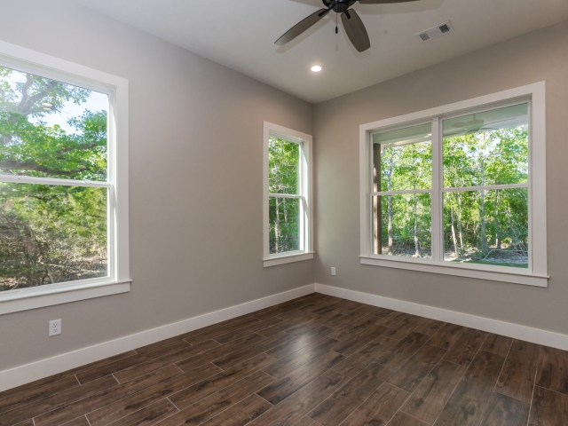 Bedroom with large windows and wood flooring.