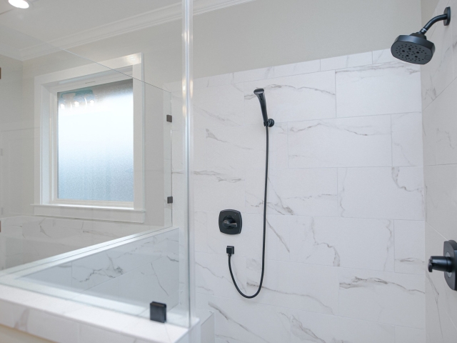 Master shower of the Antip Project with marble walls and black accents.