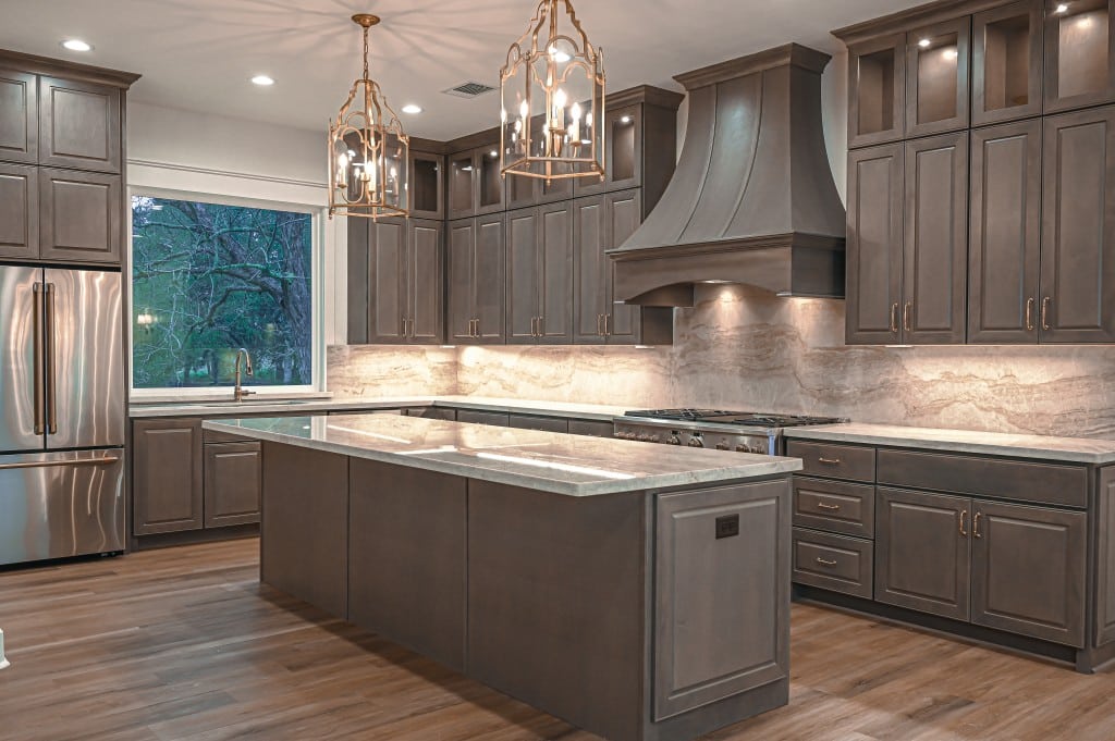 Beautiful custom built kitchen with brown cabinets and gold accent lighting.