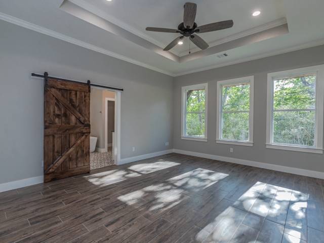 Bedroom with a wood sliding door and large windows.