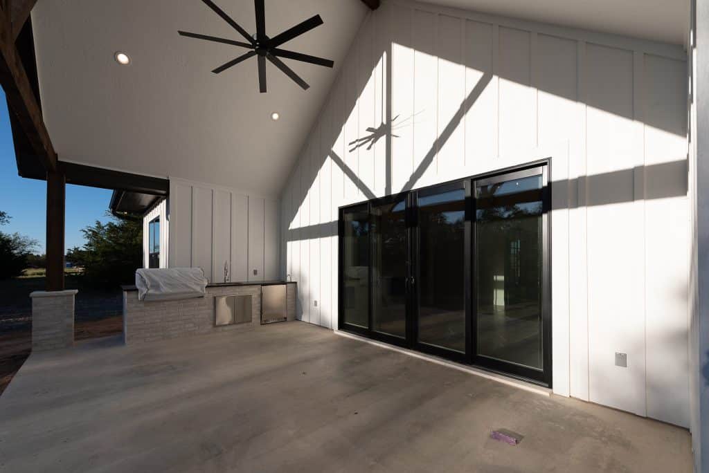 Outdoor living space in a custom home with high arches and a large outdoor ceiling fan.
