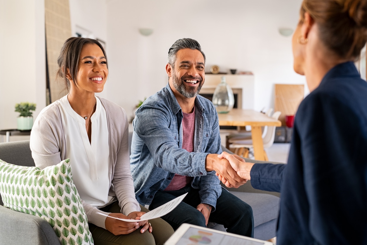 A couple and a custom home builder shaking hands.