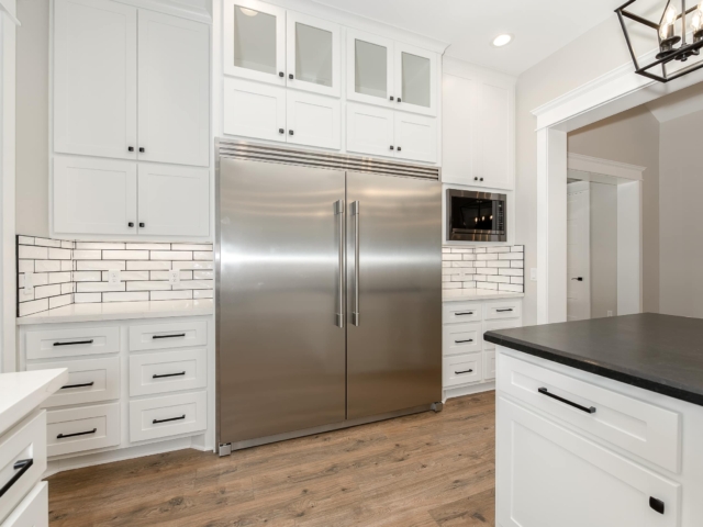 Torres Project kitchen by LaFollette Custom Homes with an industrial fridge and white aesthetic.