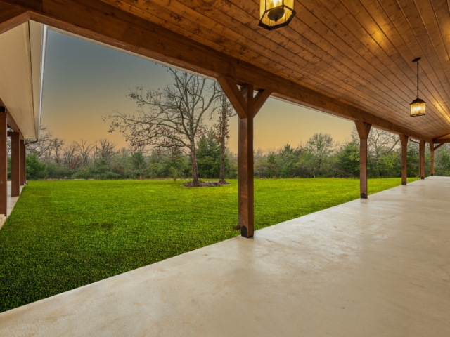The Washburn Project&#039;s porch overlooks a lush lawn from under the wood detailing.