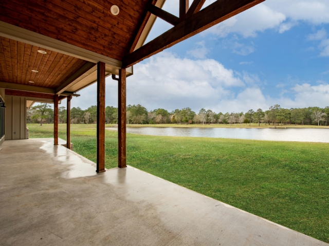 Rear porch of the Shepard Custom Home with wood detailing and view of a lush lawn and water feature.