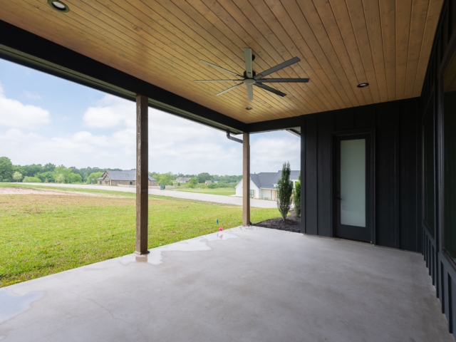 The Lakecrest Custom Home rear porch features black detailing and a view of the lawn.