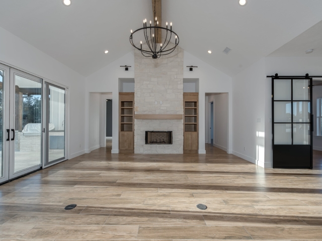 Unfurnished living room of the Berryman Project by LaFollette Custom Homes with chandelier and wood flooring.