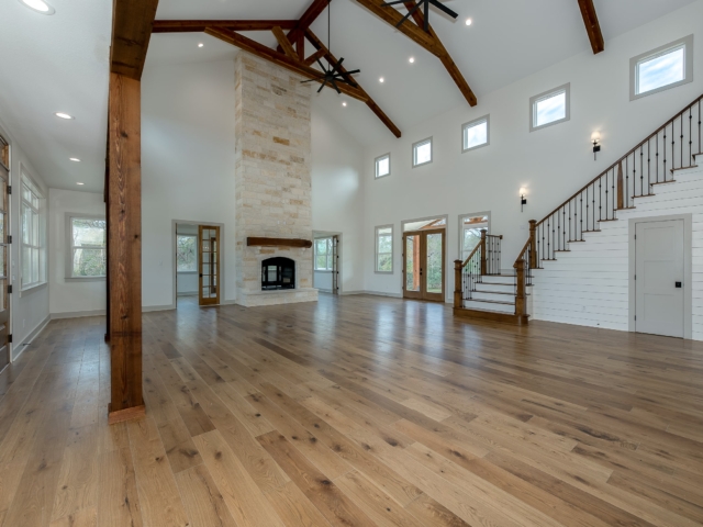 Living room of the Hovey Project by LaFollette Custom Homes featuring a grand fireplace and staircase.