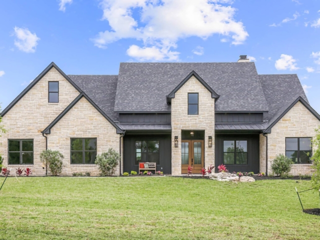 The Lakecrest Project with a stone exterior and dark roof.
