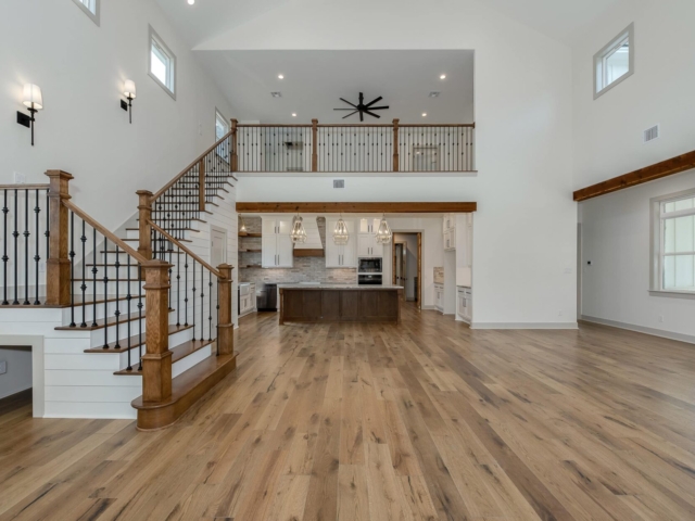 Living room of the Hovey Project by LaFollette Custom Homes, with stunning staircase and wood flooring.