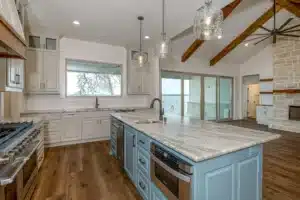 Trending kitchen features with white counter tops, blue cabinets, white walls, and brow wood flooring.