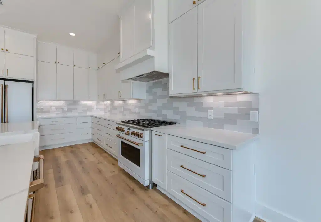 Current image: Modern kitchen with white cabinets and appliances, light brown wooden floors, and soft under-cabinet lighting for a warm, inviting ambiance.