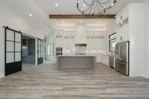 Modern kitchen with white cabinets, gray island, stainless steel appliances, and sliding glass barn doors.