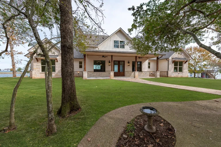 Front yard with pavement leading to one story house with white bricks.